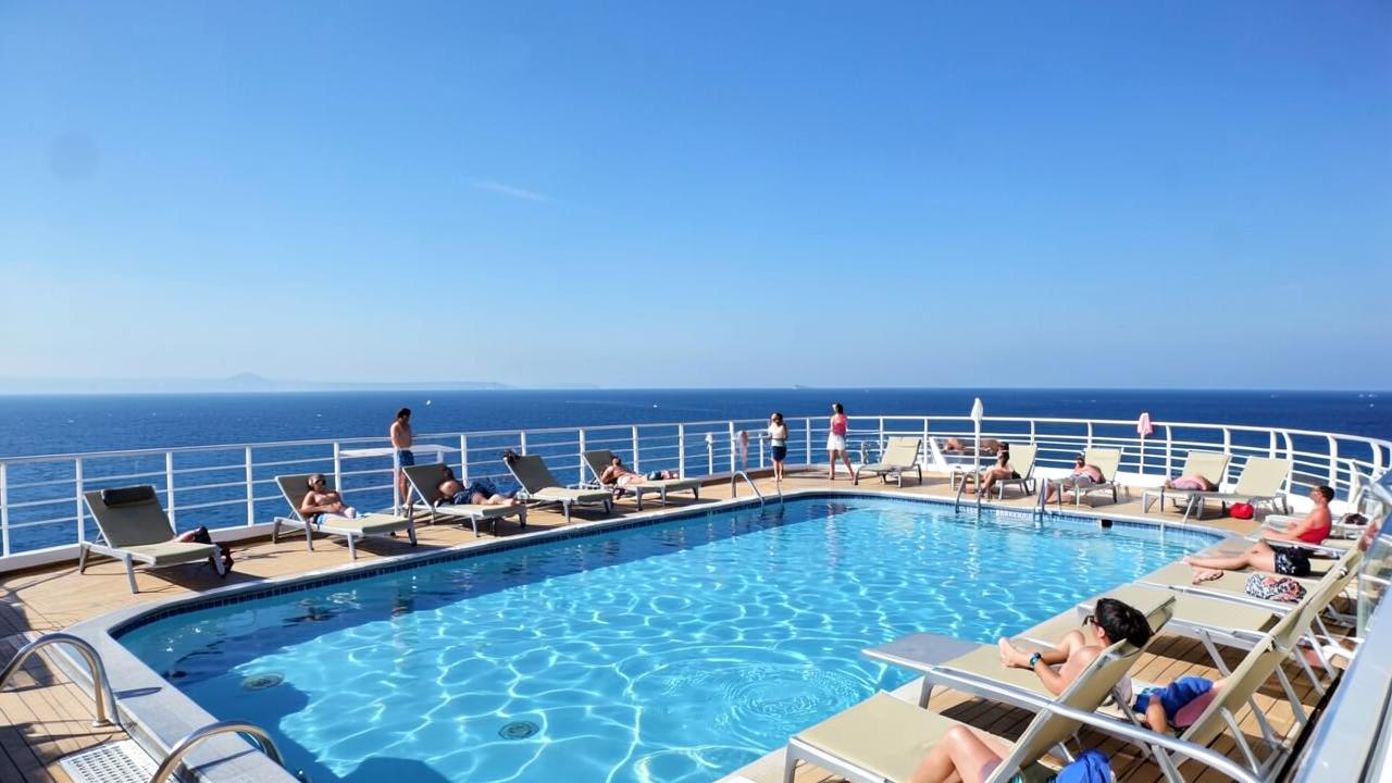 Deck superior de navio de cruzeiro com piscina e espreguiçadeiras ao sol